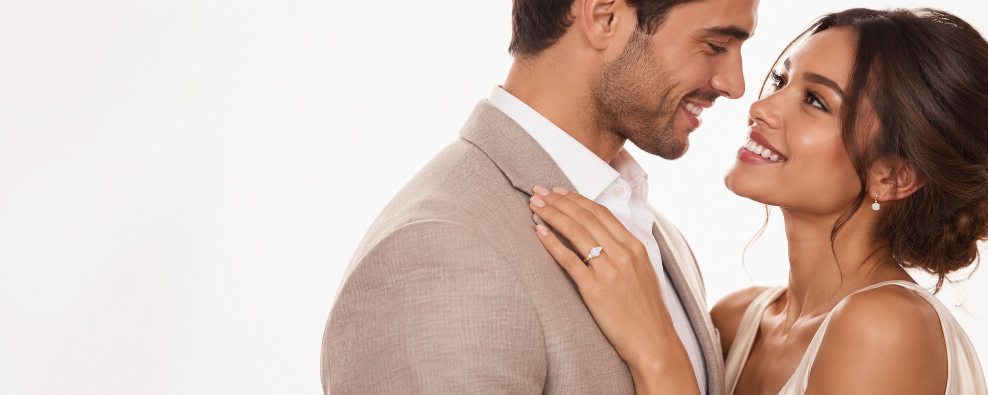 A couple smiling at each other, her engagement ring on his shoulder